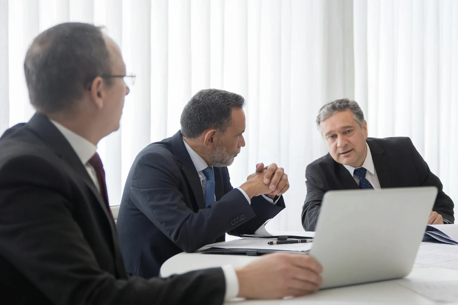 Trois hommes d'affaires discutent devant un écran